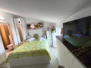 a small bedroom with a bed and a flat screen tv at Apartments and rooms Roberto B. in Valun