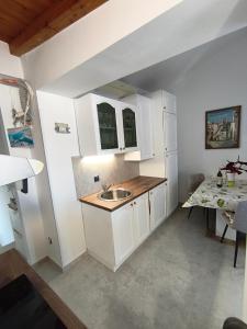 a kitchen with white cabinets and a sink and a table at Apartments and rooms Roberto B. in Valun