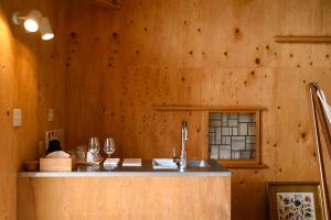 a kitchen with wooden walls and a counter with a sink at anandahの宿 in Miyazaki