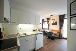 a kitchen with white cabinets and a dining room at Elslerhof in Dobbiaco
