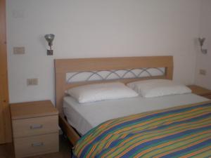 1 dormitorio con 1 cama con cabecero de madera y mesita de noche en Anna Apartment en Pozza di Fassa