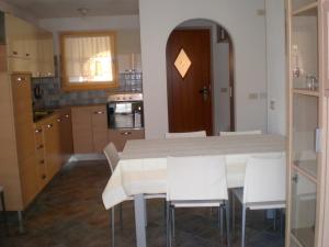 uma cozinha com uma mesa e algumas cadeiras brancas em Anna Apartment em Pozza di Fassa