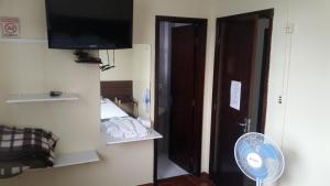 um quarto com uma cama, uma televisão e uma ventoinha em Hotel Piratini em Curitiba