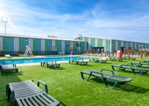 a building with a pool with benches and a playground at PMH rental in Saint Osyth