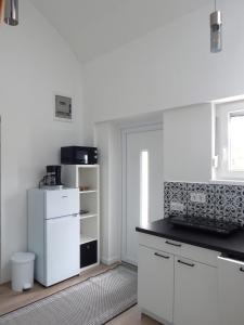 a kitchen with white cabinets and a black counter top at JundJ Ferienwohnungen in Buzsák +5 photos
