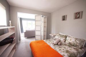 a bedroom with a bed with an orange blanket at Betty's Bay Cottage in Bettyʼs Bay