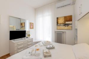 a white bedroom with a bed and a tv at Villa Atusca - Castiglioncello in Castiglioncello