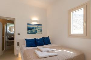 a bedroom with a bed with blue pillows and a window at Villa Karras - Sea & Mountain View in Perissa