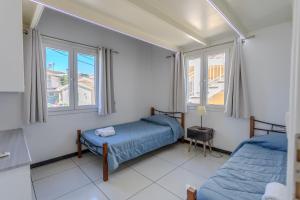 a bedroom with two beds and two windows at Mario's Kassiopi in Kassiopi