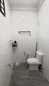 a bathroom with a white toilet in a room at UMRA Homestay in Kampong Padang Kemunting +24 photos