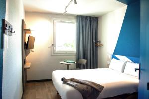 a hotel room with a bed and a window at ibis budget Bordeaux Sud in Villenave-dʼOrnon