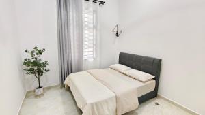 a white bedroom with a bed with a black headboard at UMRA Homestay in Kampong Padang Kemunting