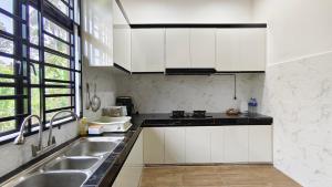 a kitchen with white cabinets and a sink at UMRA Homestay in Kampong Padang Kemunting