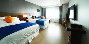 ein Hotelzimmer mit zwei Betten und einem Fernseher in der Unterkunft Login Hotel in Jeju-do + 14 Fotos