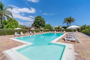 a large swimming pool with lounge chairs and umbrellas at Pathos Retreat Pool and Garden in Syracuse