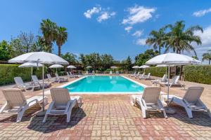 a pool with lounge chairs and umbrellas next to at Pathos Retreat Pool and Garden in Syracuse