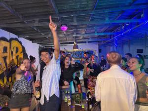 a group of people standing in a room with their hand in the air at Santara Hostel in Vang Vieng