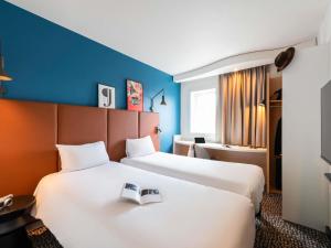 a hotel room with two beds with a book on it at ibis Chalon Sur Saone Nord in Chalon-sur-Saône +55 photos