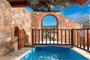 a swimming pool on a balcony with a stone wall at Elounda Monastiri Cretan sea view house with pool in Epáno Eloúnda +12 photos