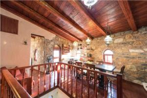 a large room with a stone wall and a wooden ceiling at Elounda Monastiri Cretan sea view house with pool in Epáno Eloúnda