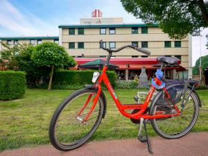 a red bike parked in front of a building at ibis Tilburg in Tilburg