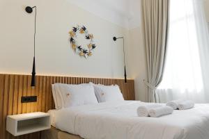 a bedroom with a white bed with towels on it at Kismet Urban Boutique in Heraklio