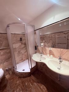 a bathroom with two sinks and a shower at Sidan Hotel Restaurant & Pizzeria in Schwendau