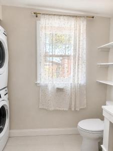 a white bathroom with a toilet and a window at Elegant Cambridge Room, Short Walk to Harvard in Cambridge +11 photos