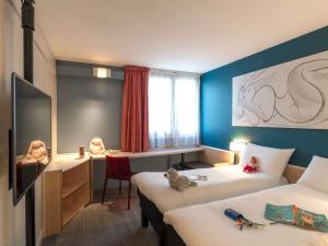 a room with two beds and a desk with two dolls at ibis Tours Nord in Tours