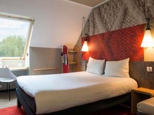 a hotel room with a large bed and a window at ibis Senlis in Senlis