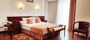 a hotel room with a bed and a chair at Hotel Europa in Ploieşti +14 photos