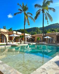 a swimming pool with palm trees in a resort at Miliyana Boutique Hotel - Adults Only in Kuta Lombok