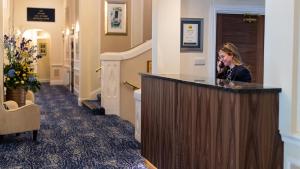 a woman talking on a phone at a counter in a hallway at The Carlyon Bay Hotel and Spa in St Austell +220 photos