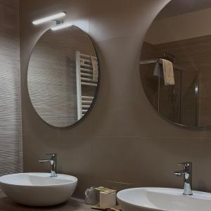 two sinks in a bathroom with two mirrors at Hotel Quadrifoglio in Caraglio