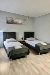 a bedroom with two beds and a painting on the wall at Apartamenty Adabet in Kępno