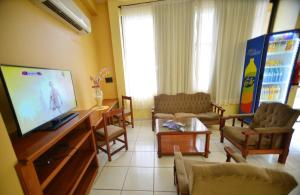 a living room with a flat screen tv and chairs at Hotel Lilian in Puerto Iguazú