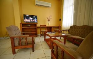 a living room with a couch and a tv and chairs at Hotel Lilian in Puerto Iguazú