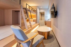 a room with bunk beds and a table and chairs at The ISA Hotel Tenjin Fukuoka in Fukuoka