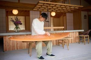 a man is holding a surfboard on a table at Villa 天ツ星 in Tahara
