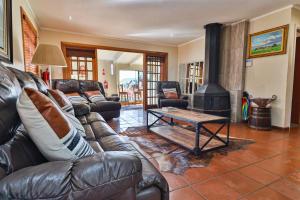 a living room with a leather couch and a fireplace at Cinzaco Dullstroom in Dullstroom