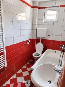 a red and white bathroom with a toilet and a sink at Apartman Sofija - Foča in Foča