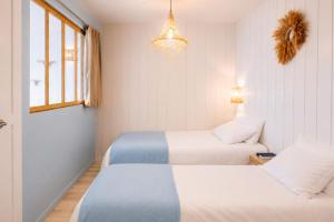 a bedroom with two beds and a window and a chandelier at Appart'Hôtel & Spa "Les Voiles" Belle Île en Mer in Carnac +9 photos