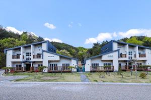 a large white building with trees in the background at Samcheok Yonghwa Silkroad Pension in Samcheok