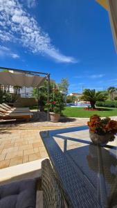 a patio with a bench and an umbrella and flowers at Villa Principessa Podstrana in Podstrana