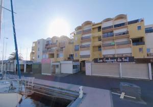 a building in front of a marina with a boat at Merveilleuse Port - Piscine - Plage - Climatisation - Commerces in Gruissan