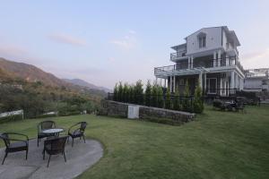 a house with chairs and a table in the yard at Maktain Glance in Dehradun