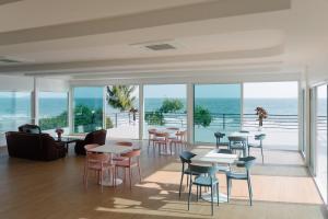 a restaurant with tables and chairs and a view of the ocean at The Princess Beachfront Resort in Ban Tha Fat