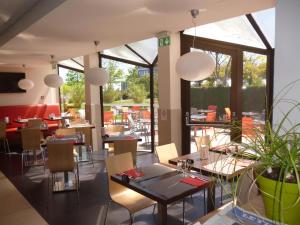 a restaurant with tables and chairs and windows at ibis Saintes in Saintes