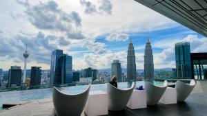 a woman sitting on the edge of a building looking at the city at Imperial KLCC Residences in Kuala Lumpur
