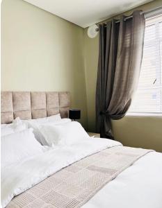 a bedroom with a bed with white sheets and a window at Premier Residence in Windermere in Durban